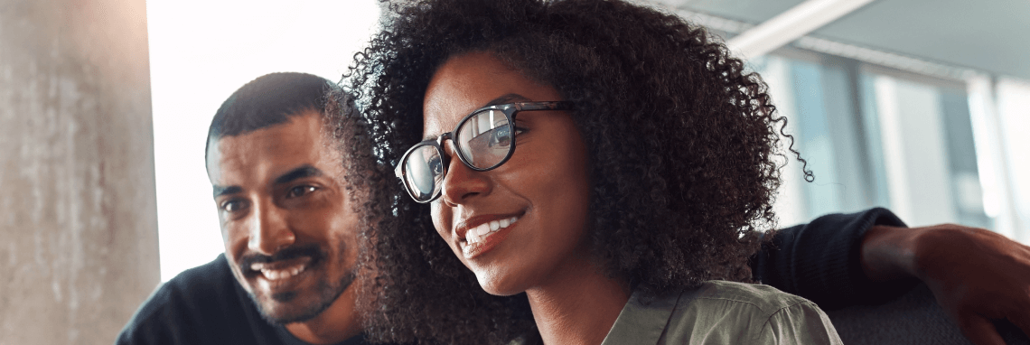 A male and Female colleague smiling looking at something together